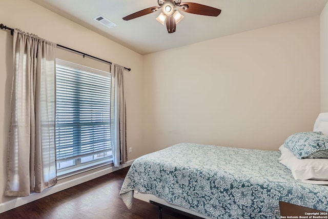 bedroom with multiple windows, dark hardwood / wood-style floors, and ceiling fan