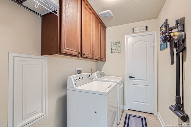 laundry room featuring independent washer and dryer, a textured ceiling, and cabinets