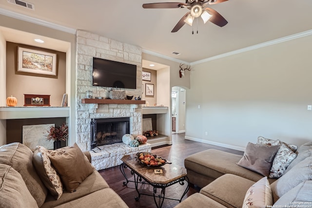 living room featuring a stone fireplace, crown molding, dark hardwood / wood-style floors, and ceiling fan