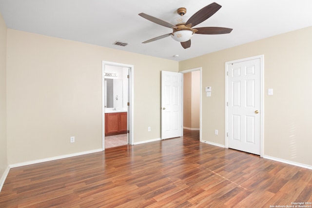 unfurnished bedroom featuring connected bathroom, dark wood-type flooring, and ceiling fan