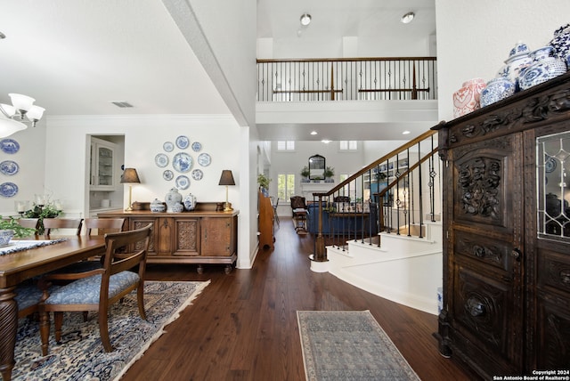 foyer with dark wood-type flooring, crown molding, and a high ceiling