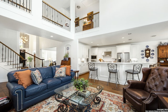 living room with sink, a notable chandelier, hardwood / wood-style flooring, and a high ceiling