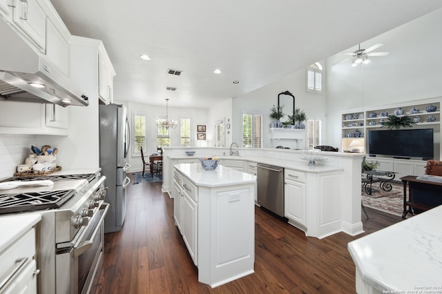 kitchen featuring dark hardwood / wood-style flooring, appliances with stainless steel finishes, a kitchen island, white cabinetry, and pendant lighting