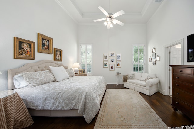 bedroom featuring a towering ceiling, a tray ceiling, dark wood-type flooring, and ceiling fan