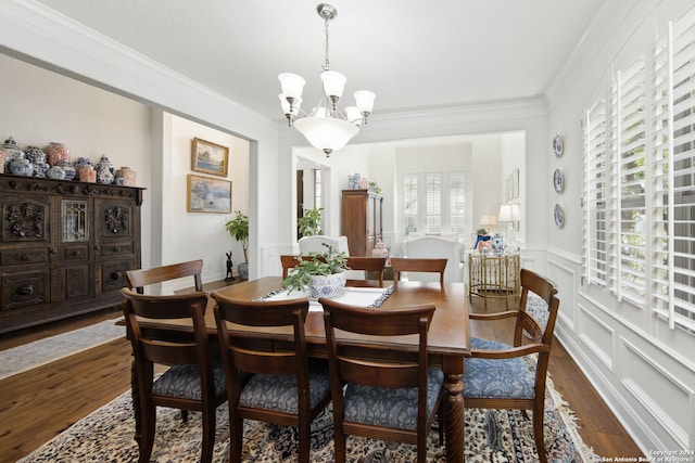 dining space with ornamental molding, a chandelier, dark wood-type flooring, and a wealth of natural light