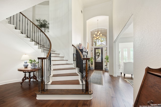 foyer entrance featuring ornamental molding, a high ceiling, a chandelier, and dark hardwood / wood-style floors