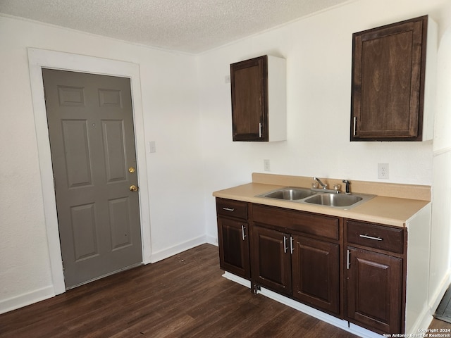 kitchen featuring dark brown cabinets, a textured ceiling, sink, and dark hardwood / wood-style floors