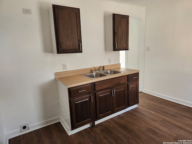 kitchen with sink, dark brown cabinetry, and dark hardwood / wood-style flooring