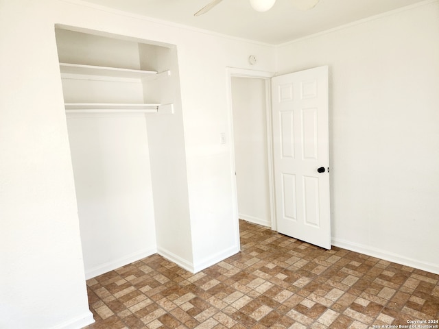 unfurnished bedroom with crown molding, ceiling fan, a closet, baseboards, and brick patterned floor