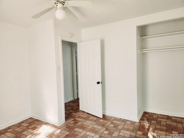 unfurnished bedroom featuring a closet, ceiling fan, brick patterned floor, and baseboards