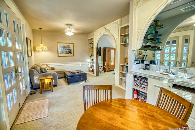 dining room featuring light carpet, french doors, built in features, and ceiling fan