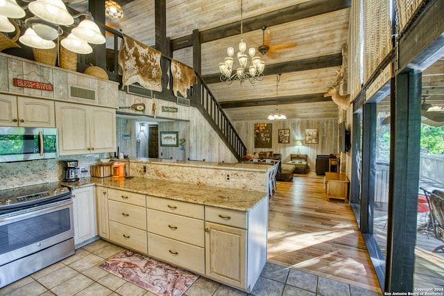 kitchen featuring appliances with stainless steel finishes, kitchen peninsula, pendant lighting, high vaulted ceiling, and an inviting chandelier