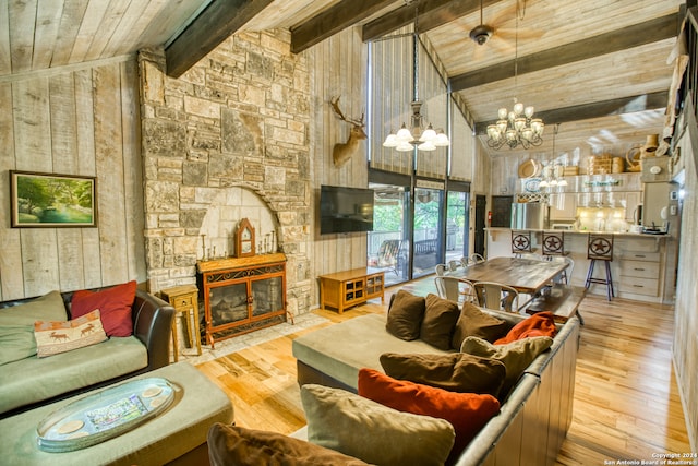 living room with wood walls, light wood-type flooring, a fireplace, beam ceiling, and high vaulted ceiling