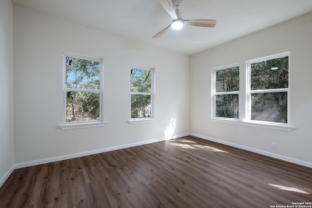 empty room with ceiling fan, plenty of natural light, and dark hardwood / wood-style flooring