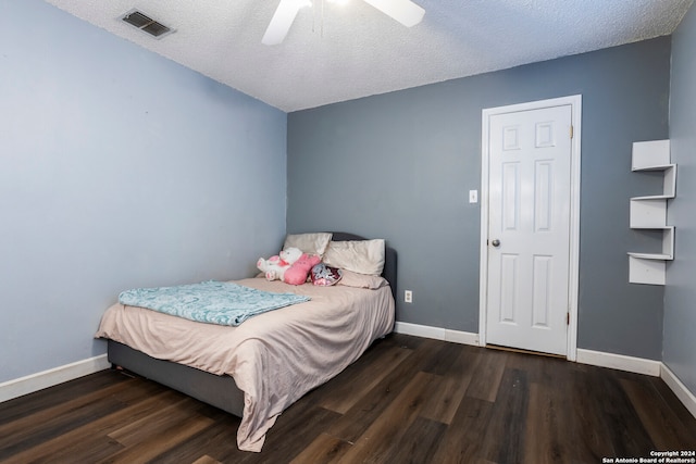 bedroom with dark wood-type flooring, a textured ceiling, and ceiling fan