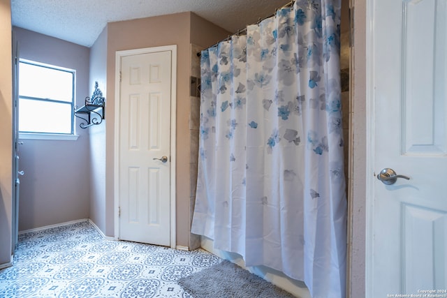 bathroom featuring curtained shower and a textured ceiling