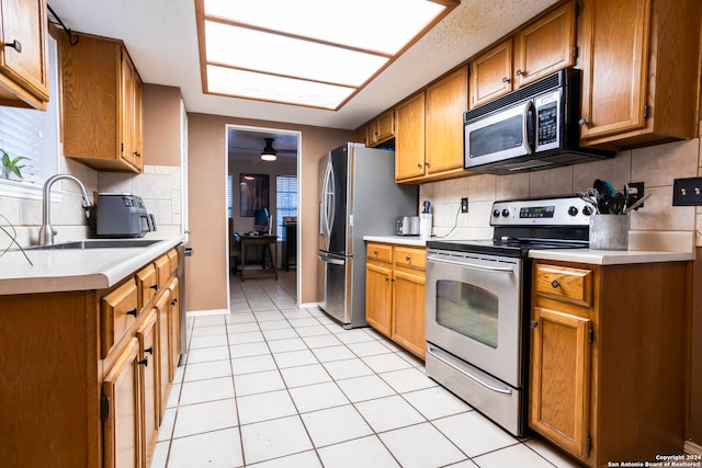 kitchen featuring decorative backsplash, stainless steel appliances, sink, and light tile patterned floors