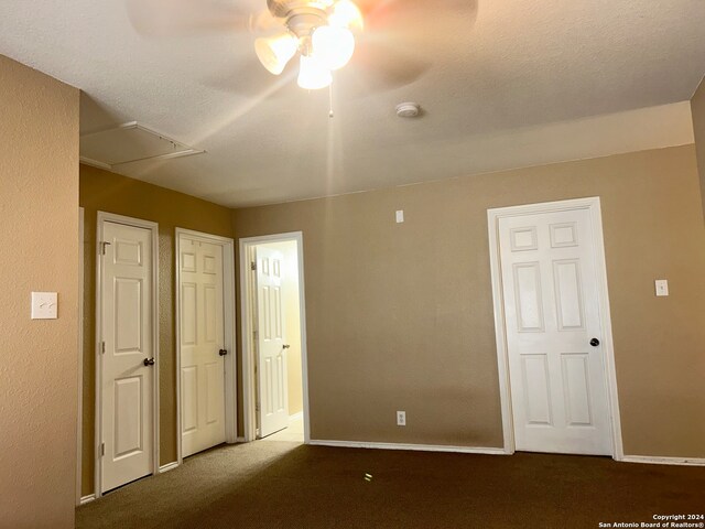 unfurnished bedroom with dark colored carpet, a textured ceiling, and ceiling fan