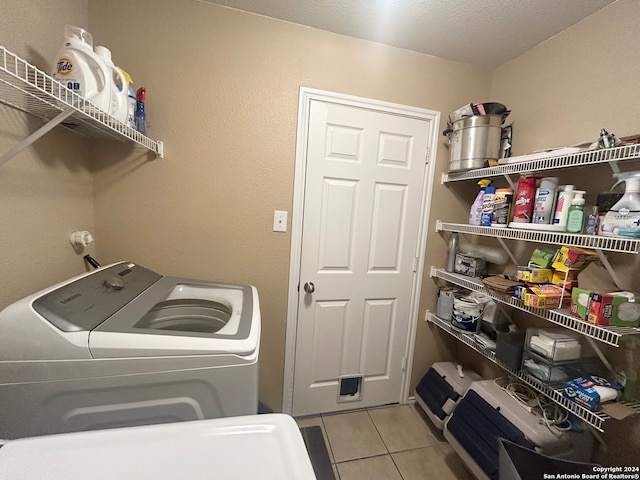 laundry area featuring a textured ceiling, light tile patterned flooring, and separate washer and dryer