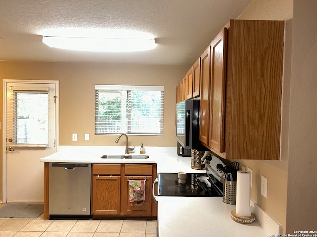 kitchen featuring a textured ceiling, stainless steel dishwasher, sink, and light tile patterned floors