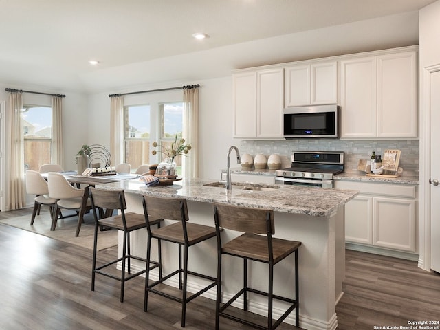 kitchen featuring dark wood-type flooring, sink, stainless steel appliances, a kitchen island with sink, and white cabinets