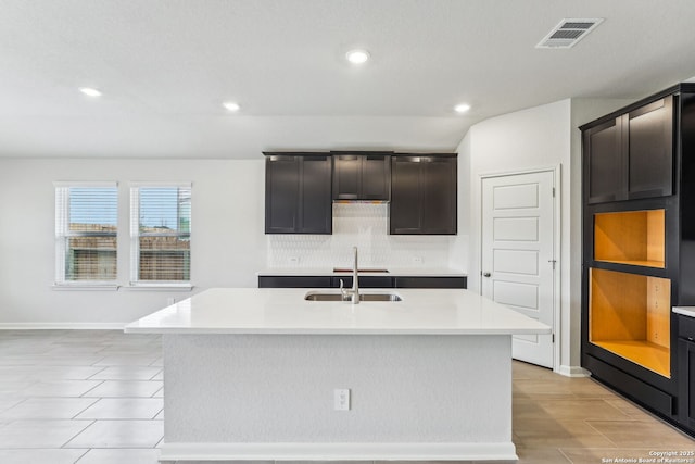 kitchen featuring tasteful backsplash, a kitchen island with sink, sink, and dark brown cabinetry