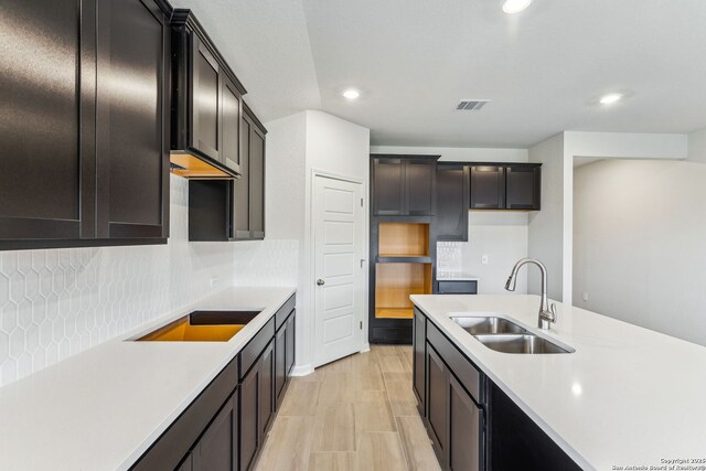 kitchen featuring tasteful backsplash, sink, black electric stovetop, and light hardwood / wood-style flooring