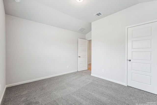 carpeted empty room with lofted ceiling