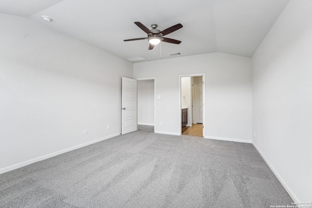 unfurnished bedroom with lofted ceiling, connected bathroom, light colored carpet, and ceiling fan