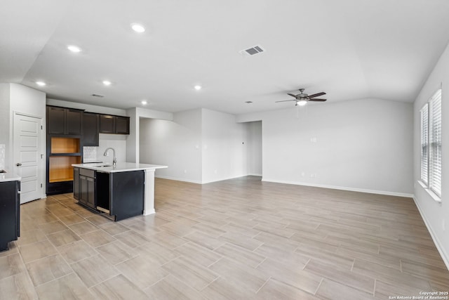 kitchen featuring sink, tasteful backsplash, vaulted ceiling, a center island with sink, and ceiling fan