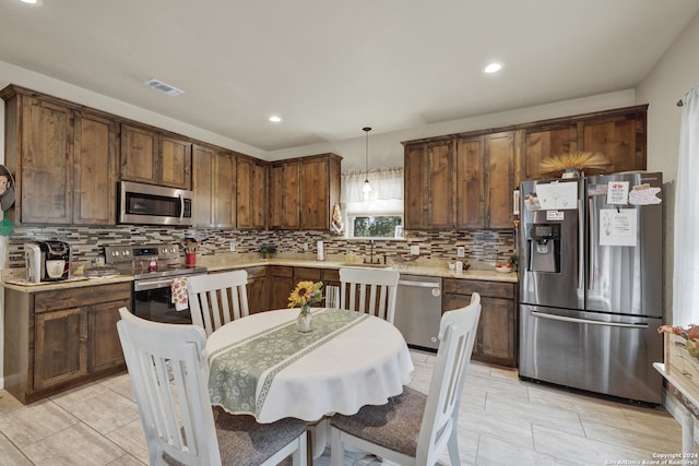 kitchen with dark brown cabinets, stainless steel appliances, hanging light fixtures, and backsplash