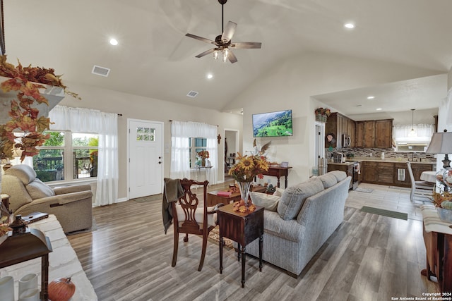 living room featuring light hardwood / wood-style floors, high vaulted ceiling, and ceiling fan