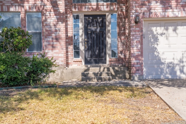 view of exterior entry with a yard and a garage