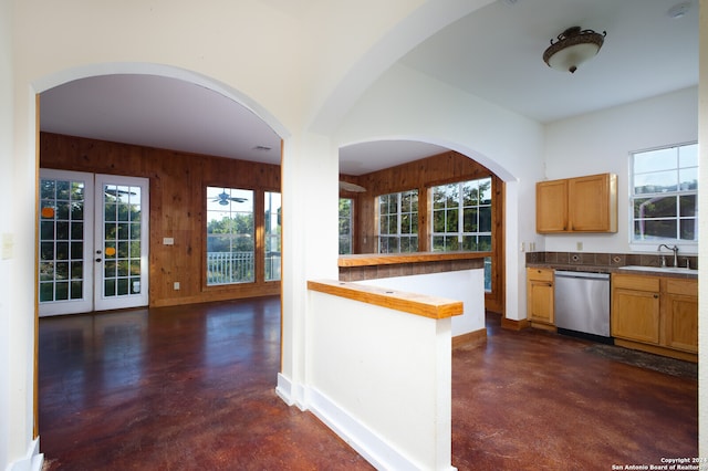 kitchen featuring wooden walls, wooden counters, french doors, stainless steel dishwasher, and sink