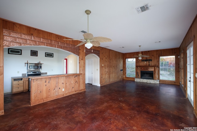 kitchen with ceiling fan, wood walls, and stainless steel appliances