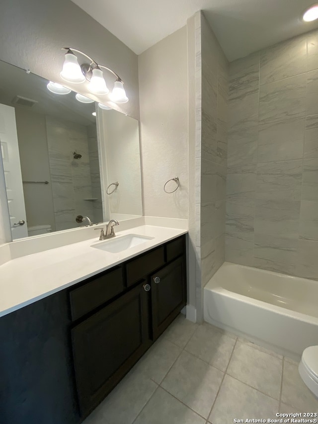 full bathroom with toilet, tiled shower / bath combo, vanity, and tile patterned flooring