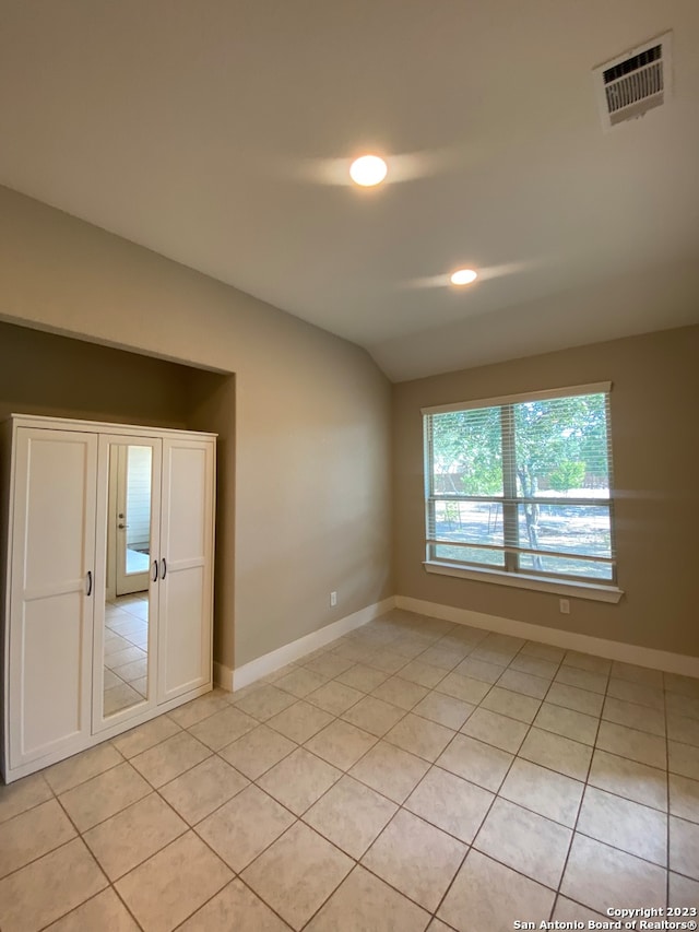 tiled spare room with lofted ceiling