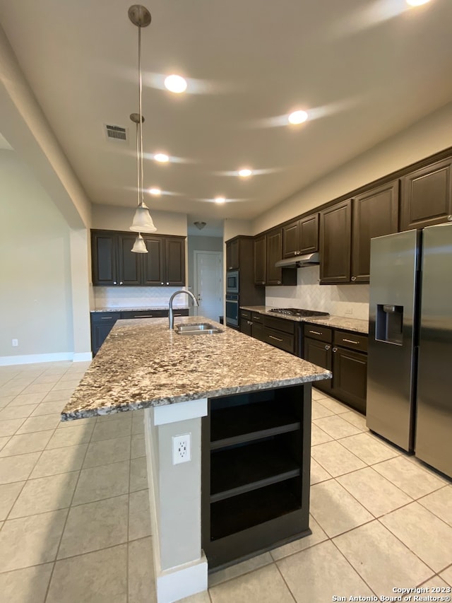 kitchen with appliances with stainless steel finishes, a kitchen island with sink, sink, and hanging light fixtures