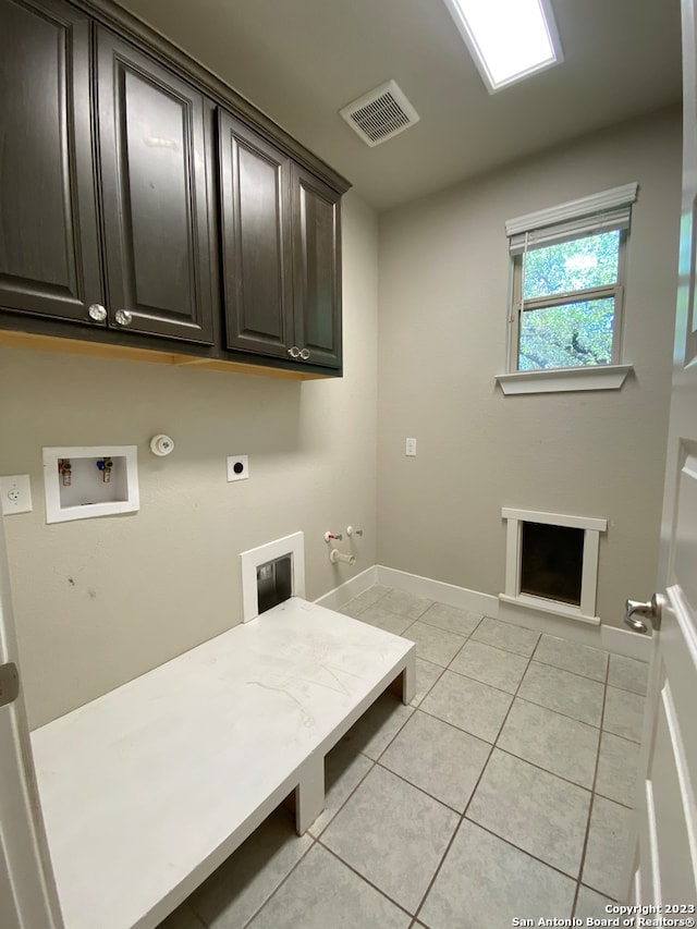 washroom with hookup for an electric dryer, hookup for a gas dryer, cabinets, washer hookup, and light tile patterned floors