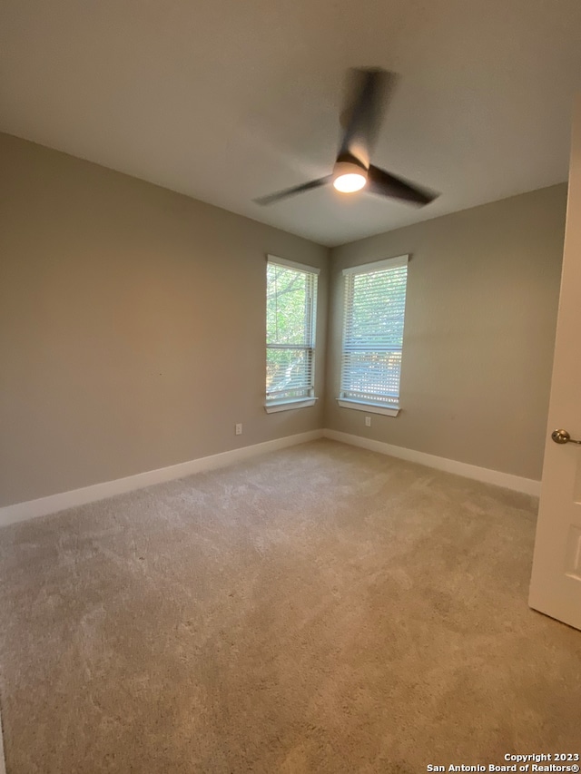 carpeted spare room featuring ceiling fan