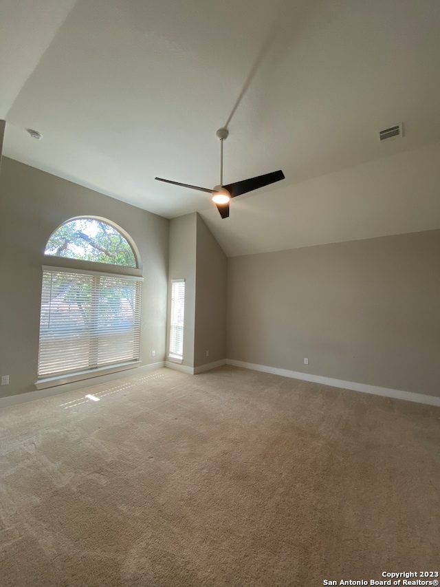 empty room with lofted ceiling, light colored carpet, and ceiling fan