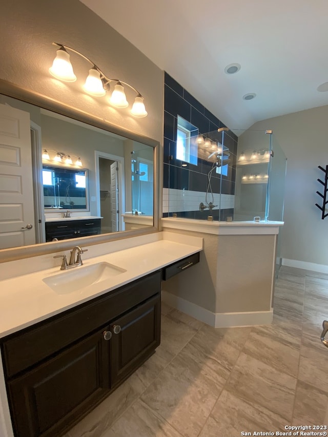 bathroom featuring vanity, a tile shower, and vaulted ceiling