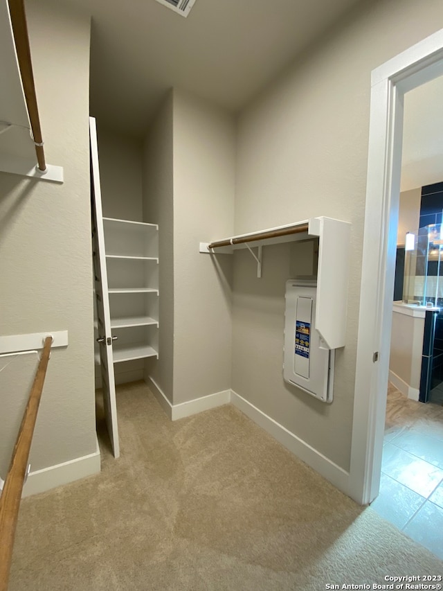 walk in closet with light carpet