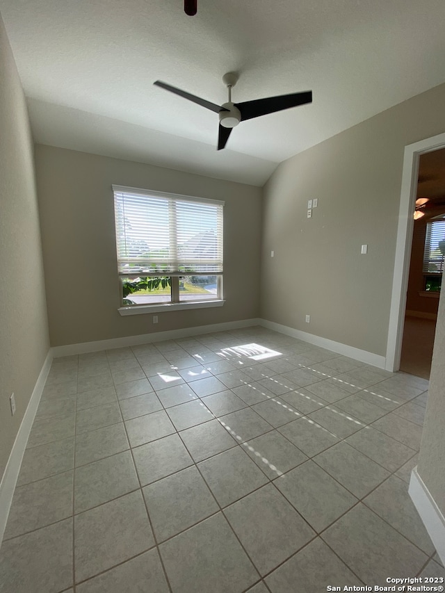 unfurnished room with ceiling fan, lofted ceiling, and light tile patterned floors