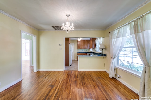 kitchen featuring light hardwood / wood-style floors, sink, hanging light fixtures, crown molding, and white refrigerator