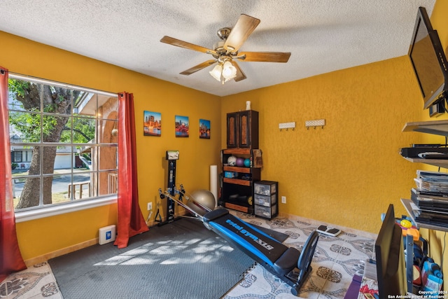 workout area featuring ceiling fan and a textured ceiling