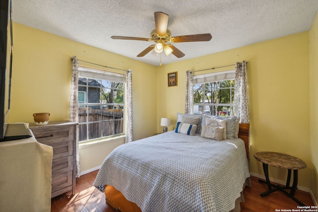 bedroom featuring a textured ceiling, dark hardwood / wood-style floors, and ceiling fan