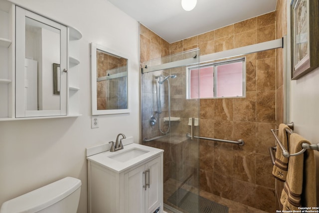 bathroom featuring a shower with door, vanity, and toilet