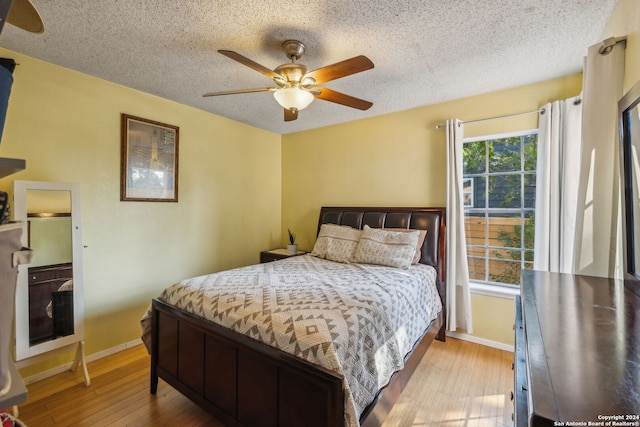 bedroom featuring light hardwood / wood-style floors, a textured ceiling, and ceiling fan