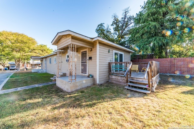 bungalow-style home featuring a wooden deck and a front lawn